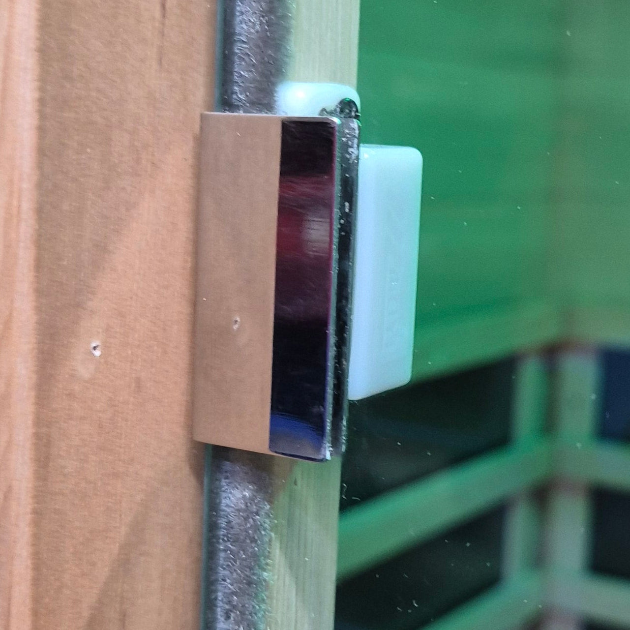 Metal door handle on a wooden door with a green background