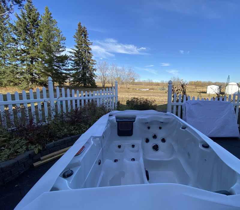 Seat jets and top-rim fittings of a hard-shell hot tub in autumn sunshine