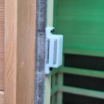 White door stopper attached to a wooden door with a green wall in the background